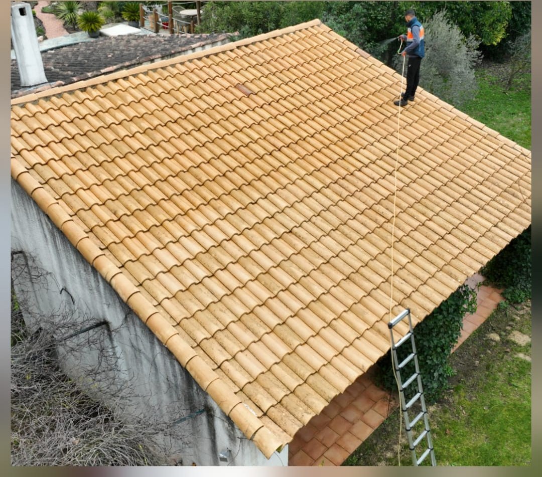 Couvreur terminant le nettoyage de la toiture, tuiles de nouveau claires, vue par drone